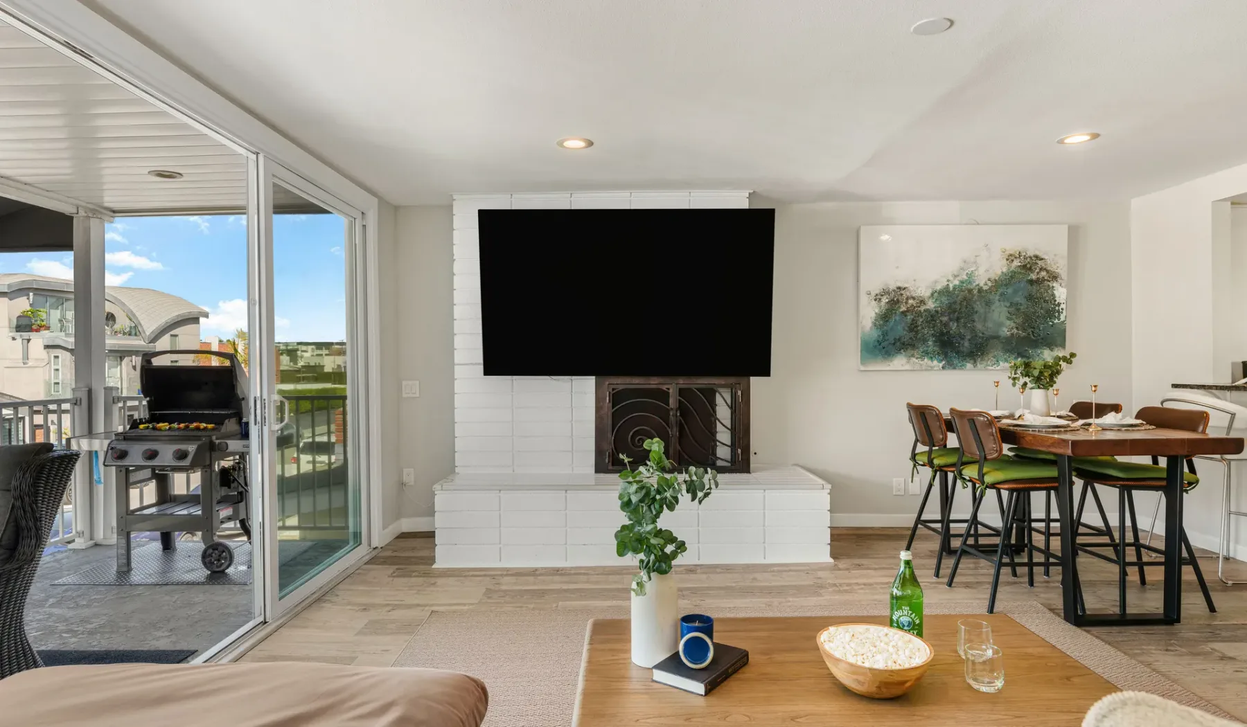 Una luminosa sala de estar y comedor cuenta con un televisor montado en la pared y una mesa de comedor.