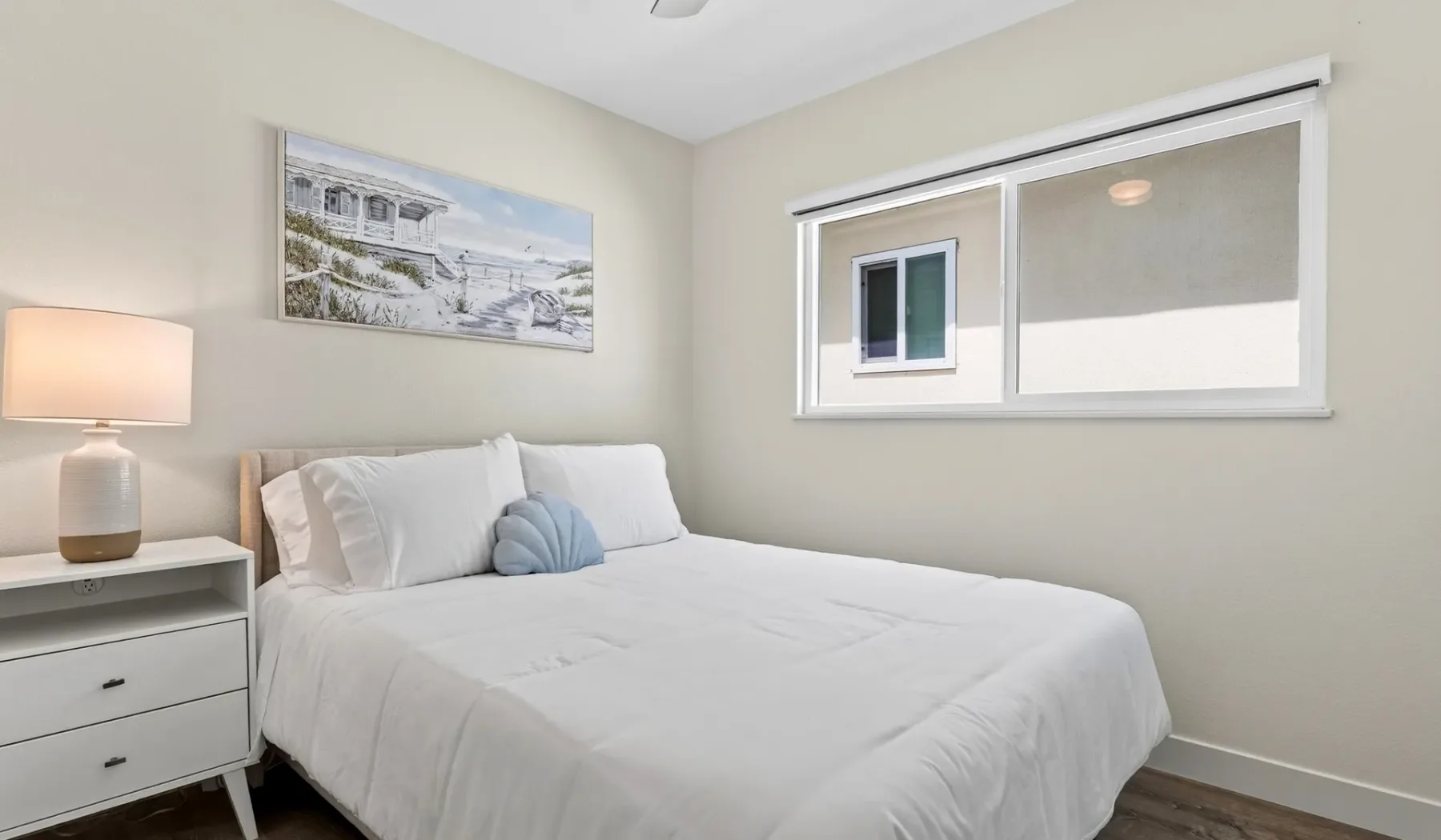 Un dormitorio con una cama tendida, una mesita de noche y una ventana.