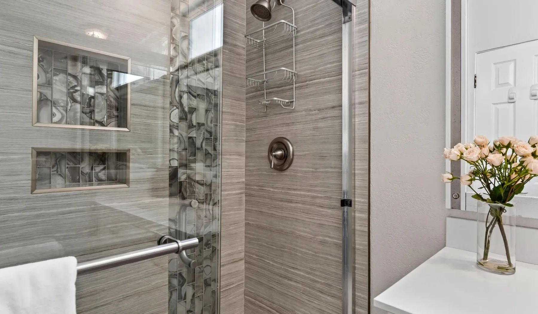 Un baño moderno con ducha de vidrio y un tocador blanco.