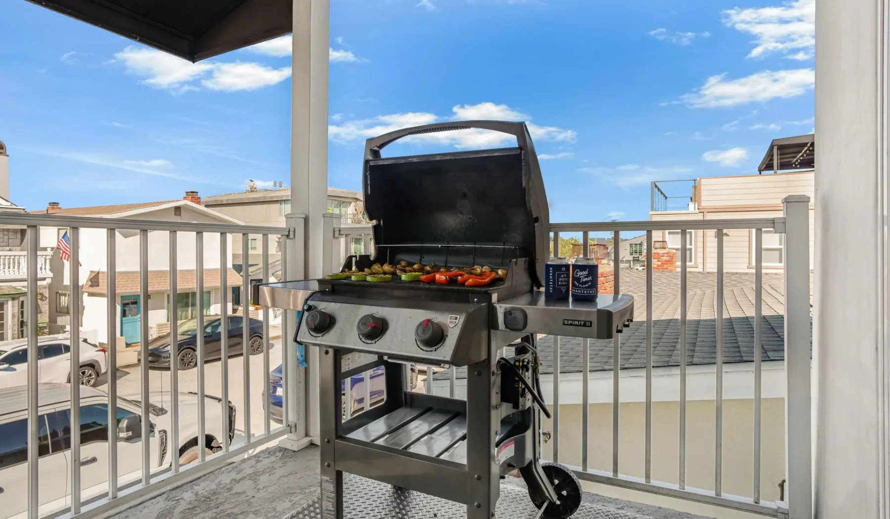 Un balcón al aire libre con una parrilla abierta y edificios vecinos a la vista.
