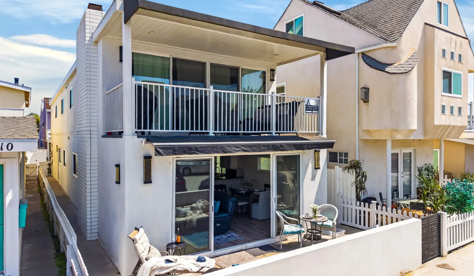 Una casa moderna de varios pisos con balcones y un patio en la planta baja.