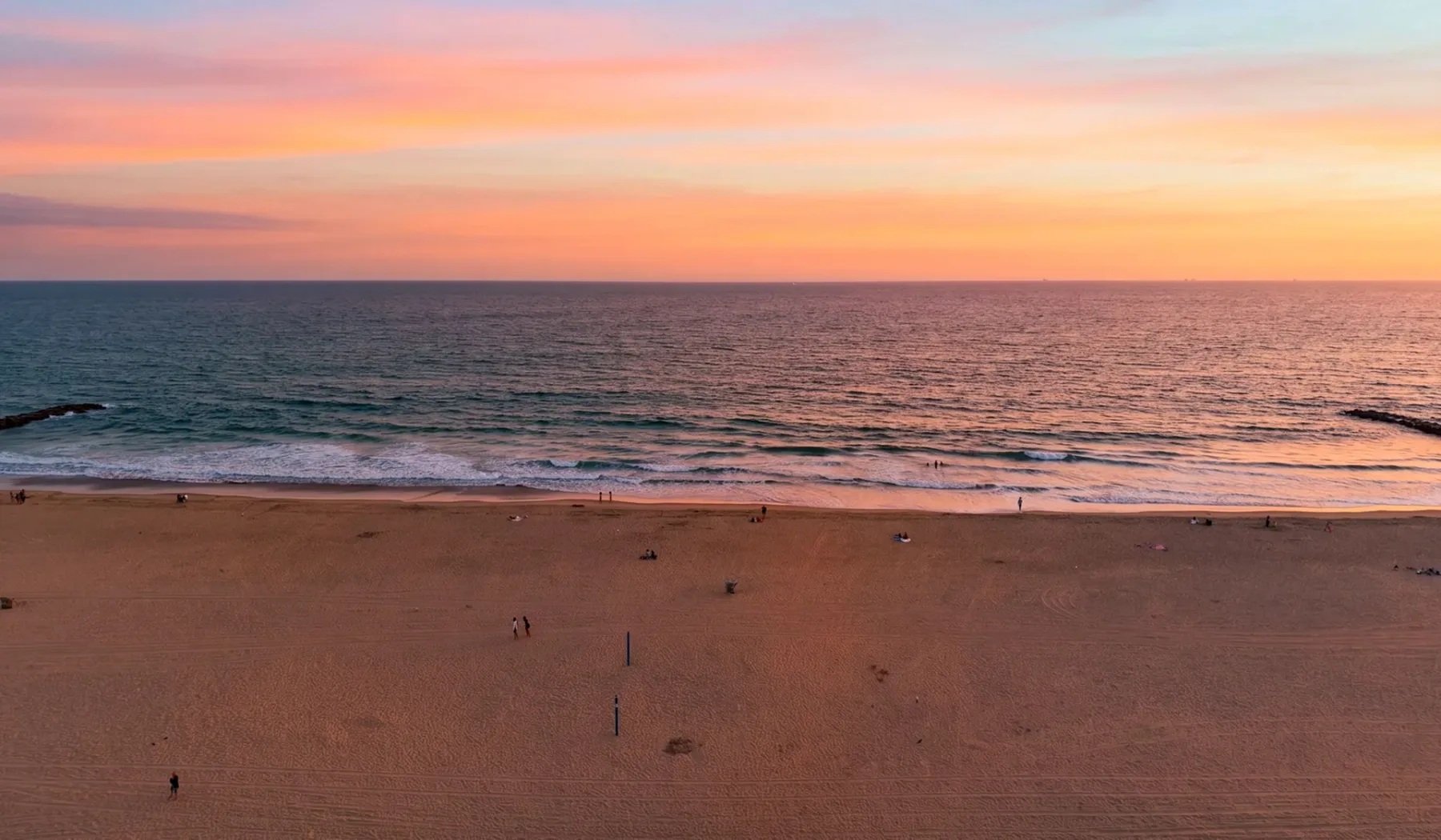 Una playa y un mar tranquilo bajo un cielo colorido al atardecer.