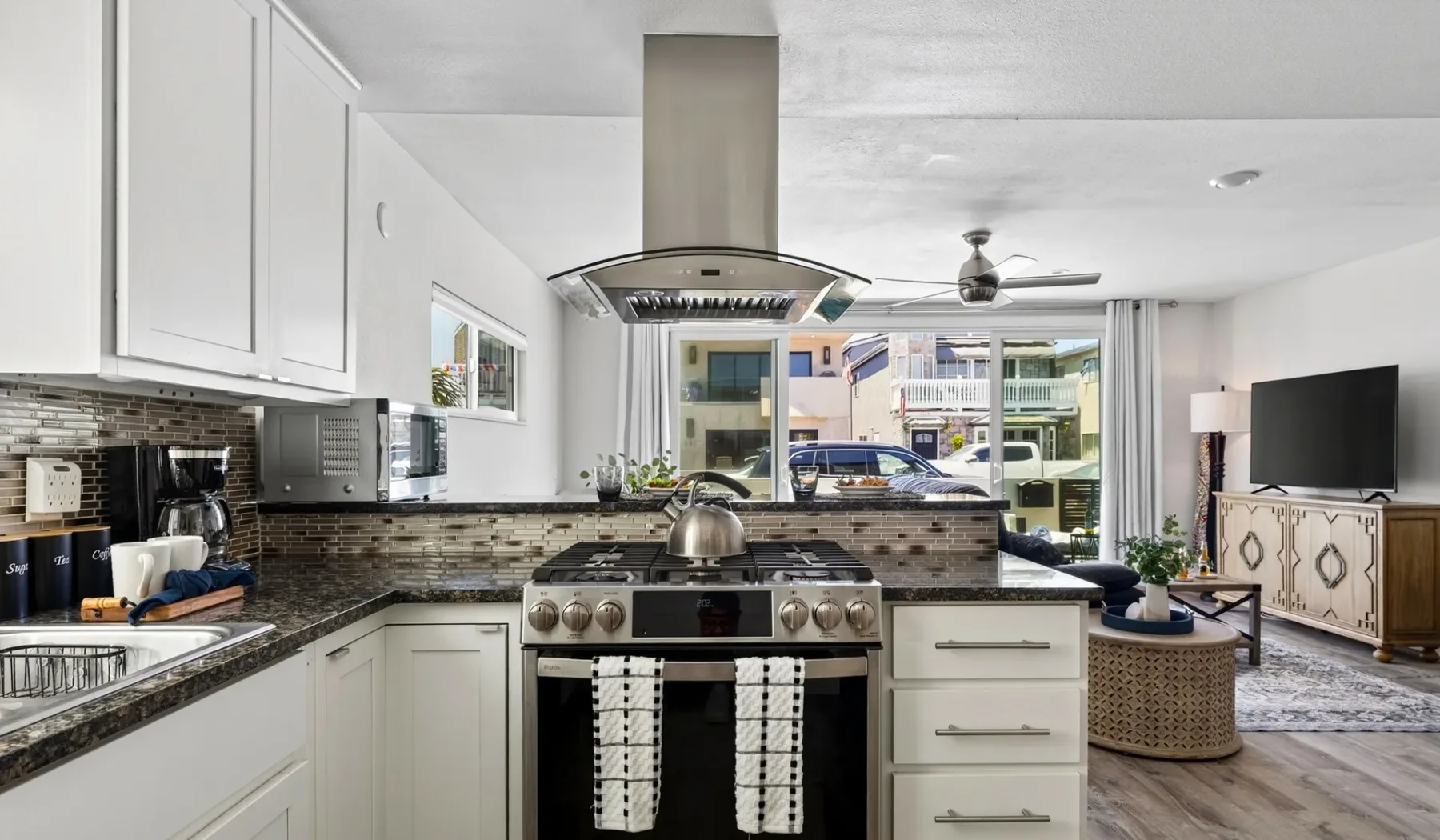 Una cocina luminosa con una estufa central, abierta a una sala de estar.