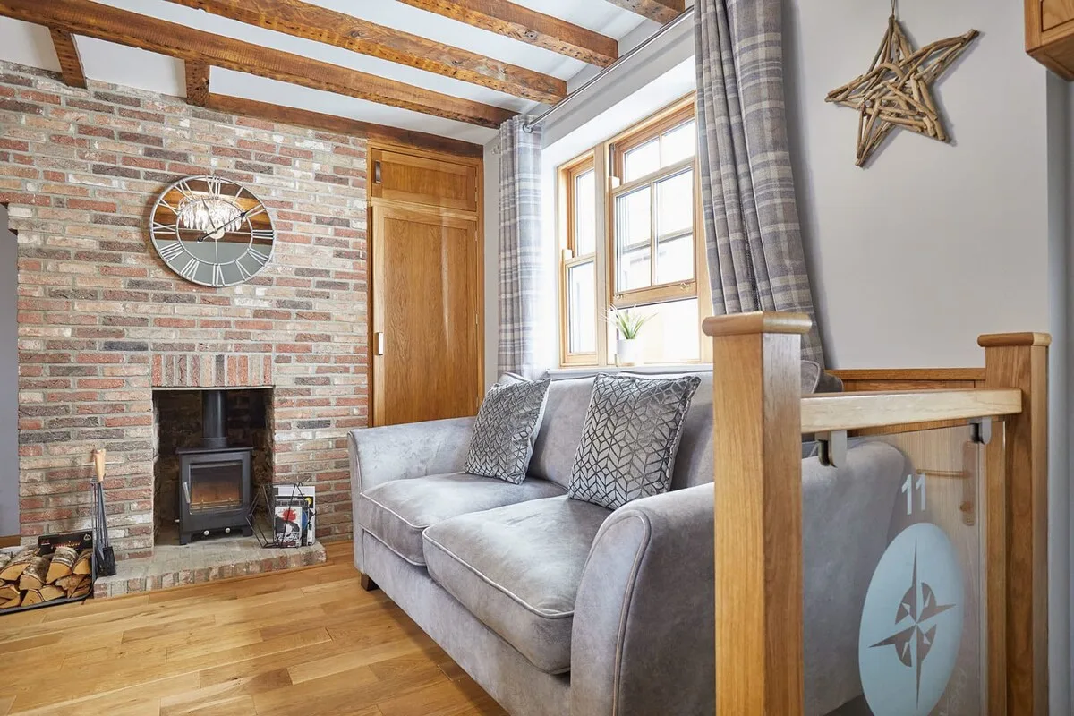 A bright living room with a gray sofa beside a brick fireplace.