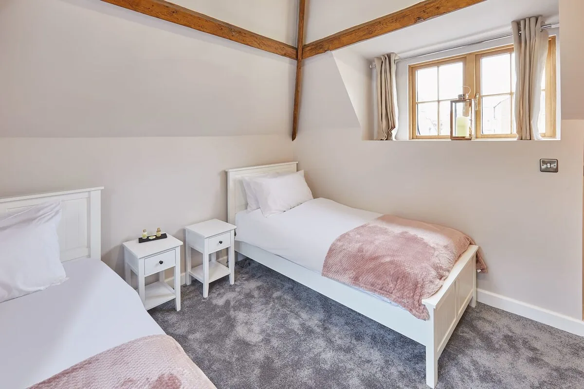 Un dormitorio luminoso con dos camas individuales y una ventana con cortinas.