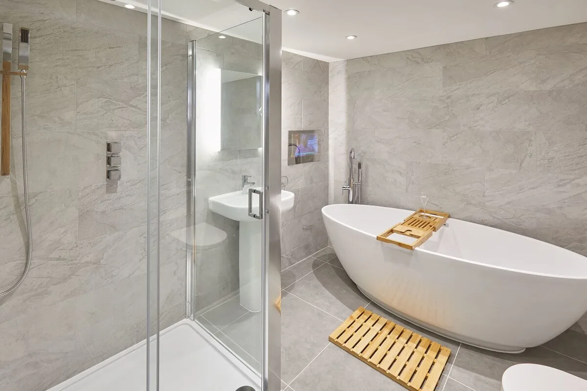 Un baño alicatado con ducha de vidrio y bañera exenta.