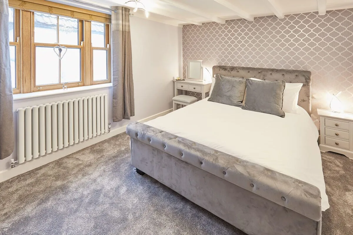 A bedroom with a large bed, bedside tables, and a window.