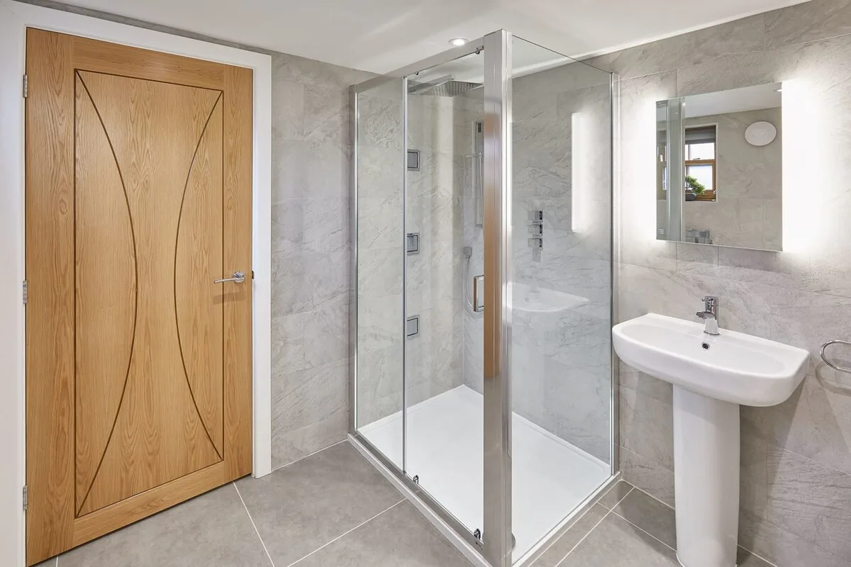 Un baño alicatado con ducha de cristal y lavabo de pedestal.