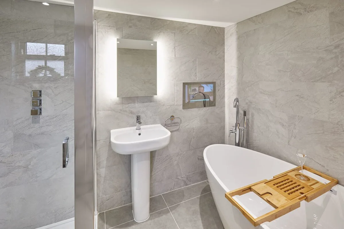 Un baño con bañera exenta, lavabo y espejo de pared.