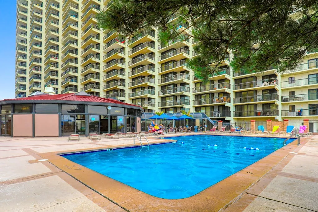 An outdoor swimming pool sits beside a high-rise building with balconies.