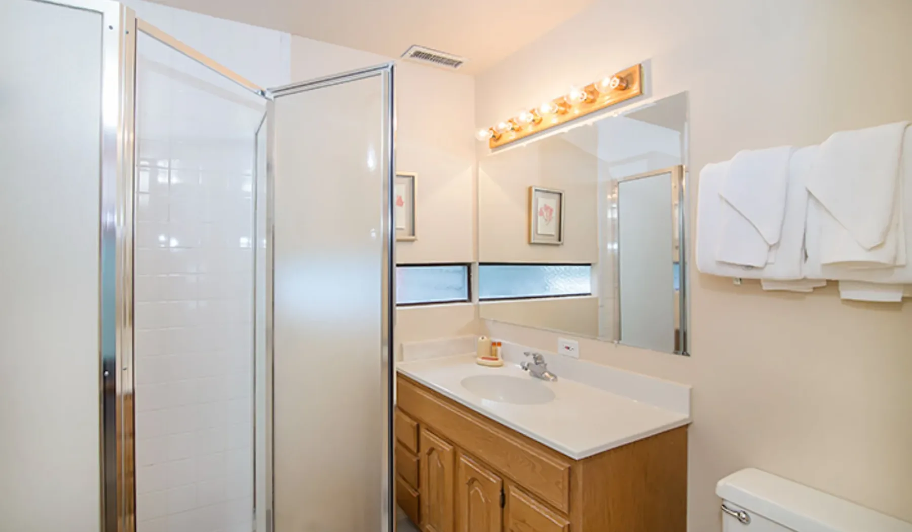 Un baño luminoso con ducha de vidrio, lavabo y espejo.
