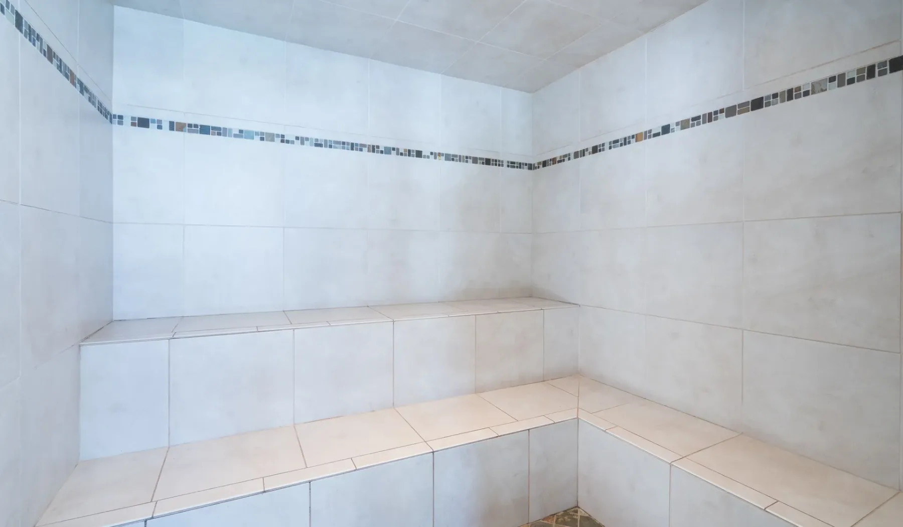 Un baño de vapor con azulejos y un banco integrado que rodea las paredes.
