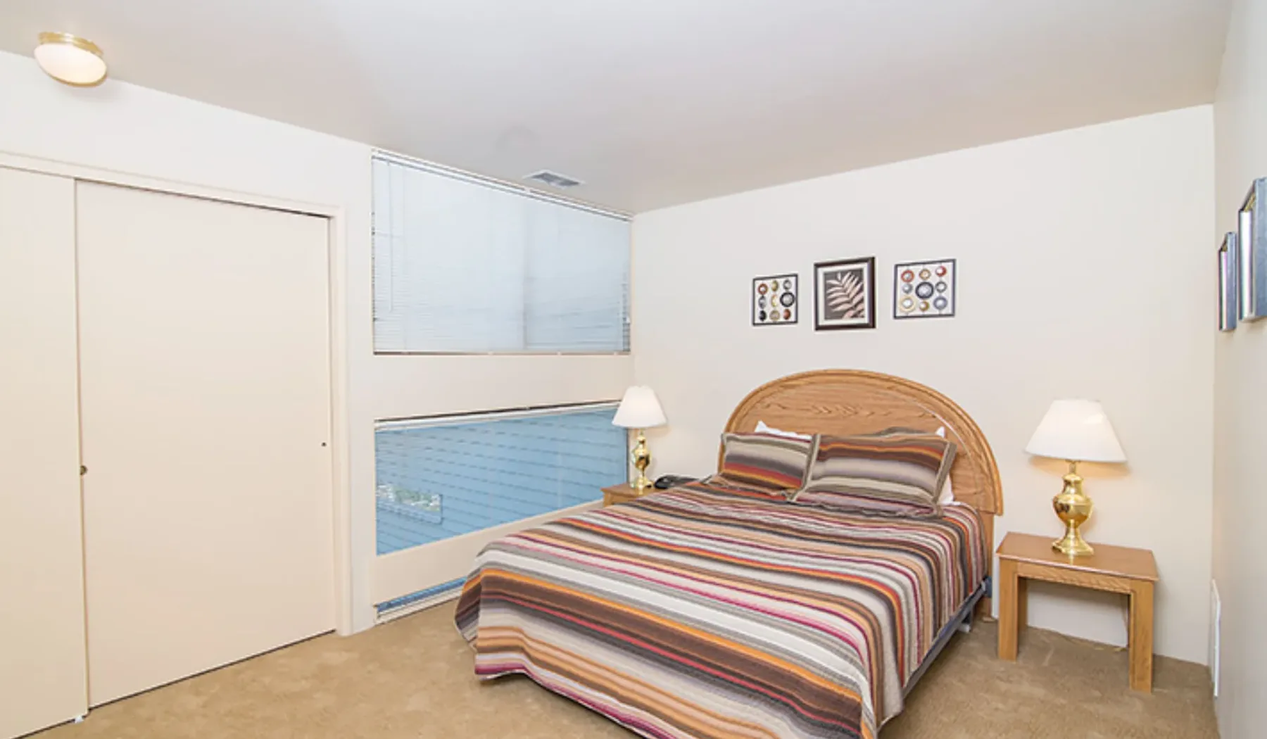 Un dormitorio con una colcha a rayas y lámparas a juego junto a la cama.