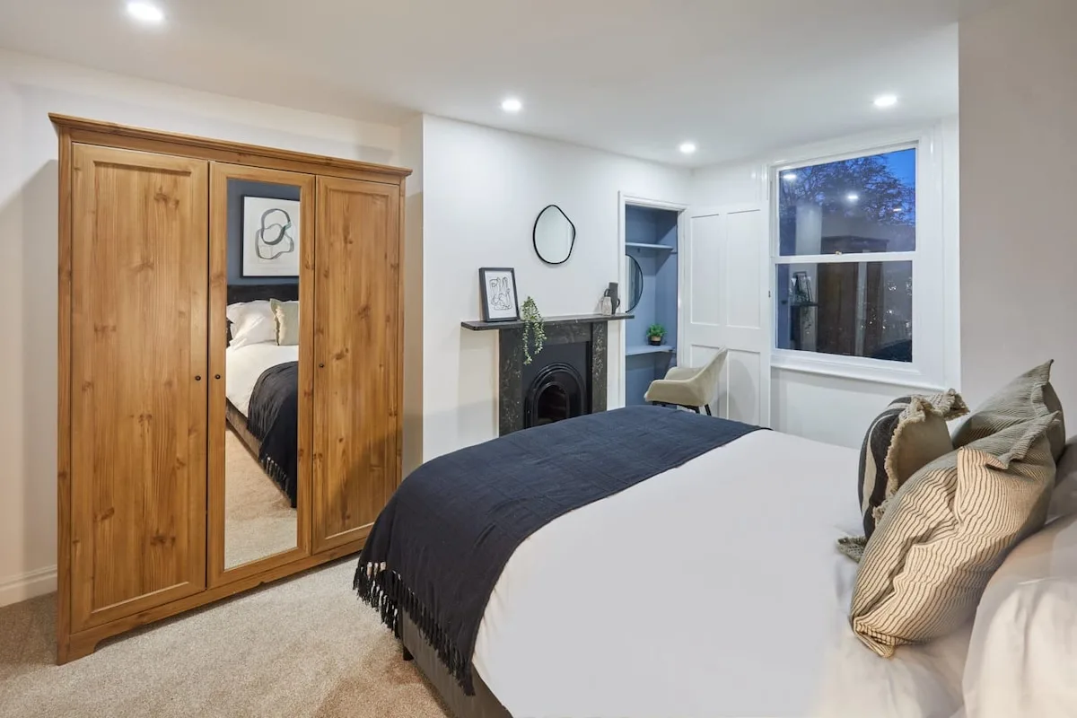 A bedroom with a bed, wooden wardrobe, and window.