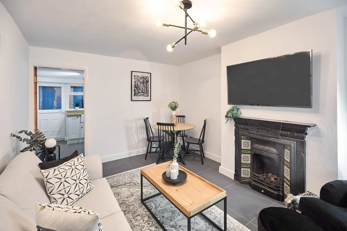 Living room with seating, a coffee table, and a television above a fireplace.