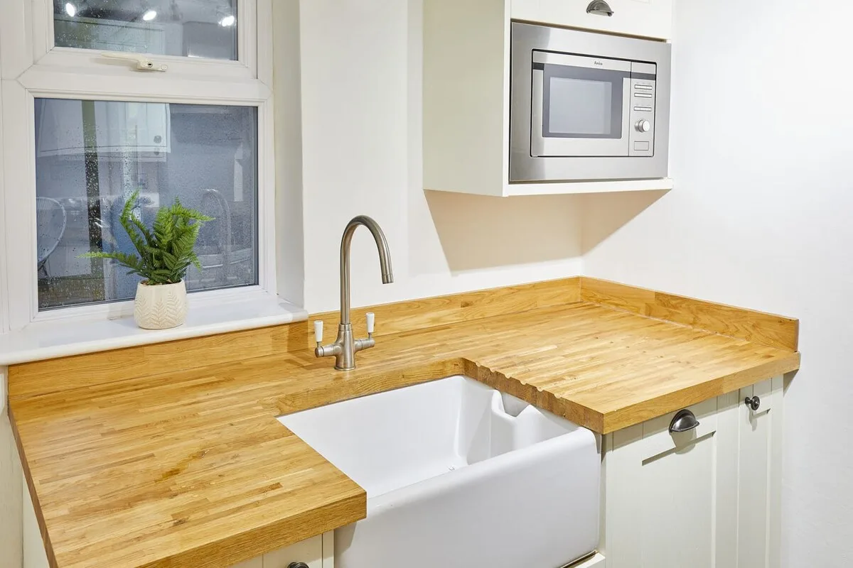 A bright kitchen with wooden countertops, a sink, and a built-in microwave.