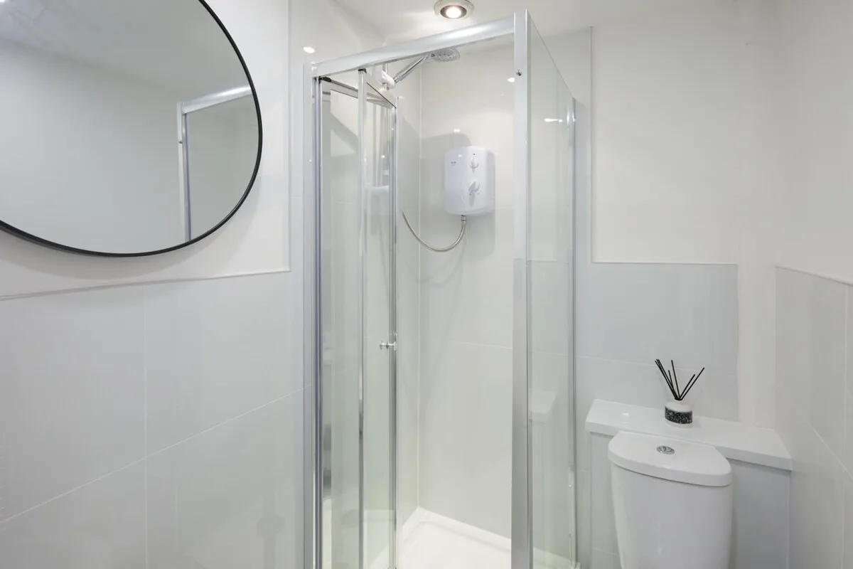 A bright bathroom with a glass shower and a wall-mounted mirror.