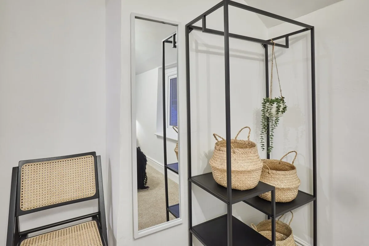 A bright room with a black display shelf holding woven baskets and a hanging plant.
