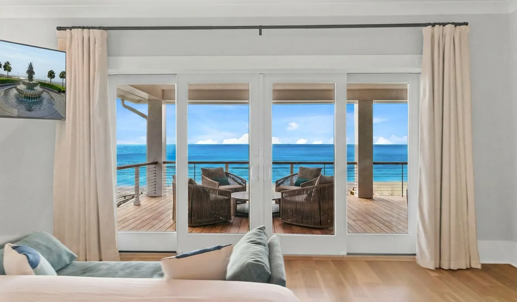 Una habitación luminosa da a un balcón con asientos y vistas al mar.