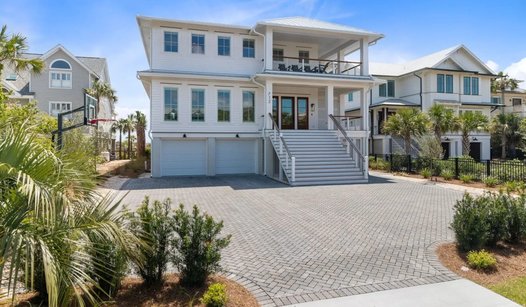 Una casa grande de estilo costero con una amplia entrada pavimentada y escalones frontales.