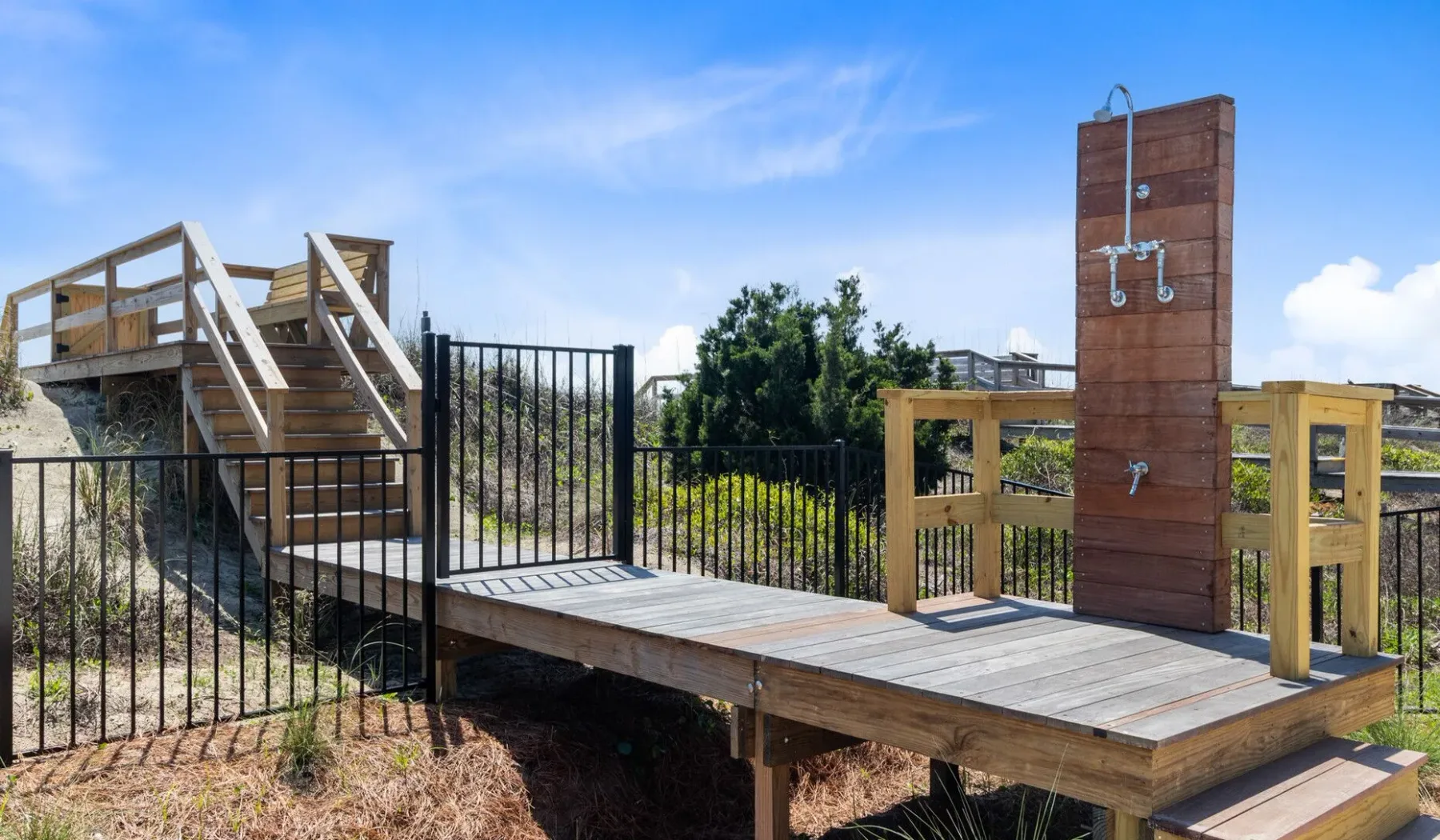 Una terraza exterior de madera con barandillas y una ducha a la vista.