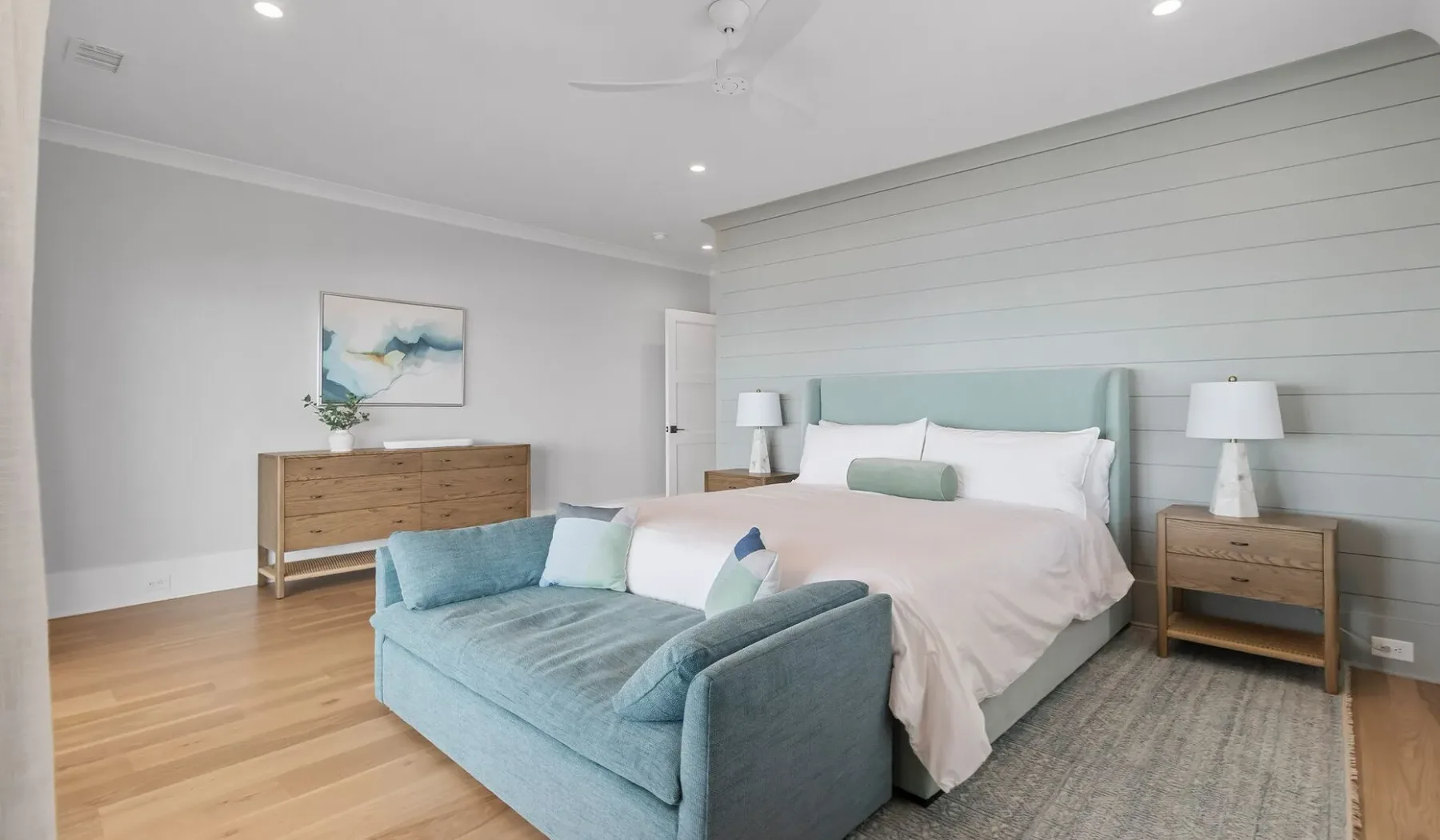 Un dormitorio luminoso con una cama con detalles azul claro y una zona de estar a juego.