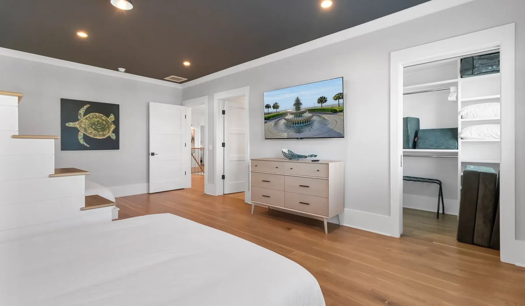 Un dormitorio con cama, cómoda y una puerta abierta a un espacio contiguo.