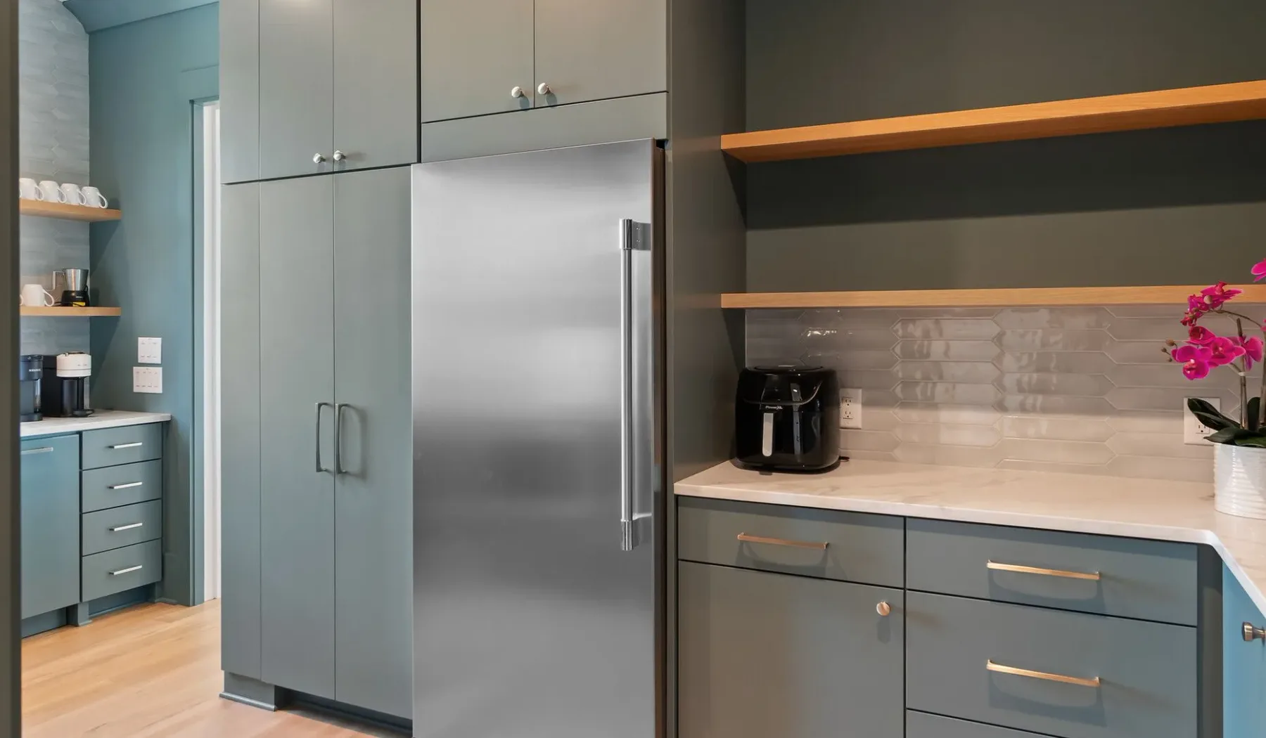 Una cocina moderna con gabinetes grises, un refrigerador y una cafetera.