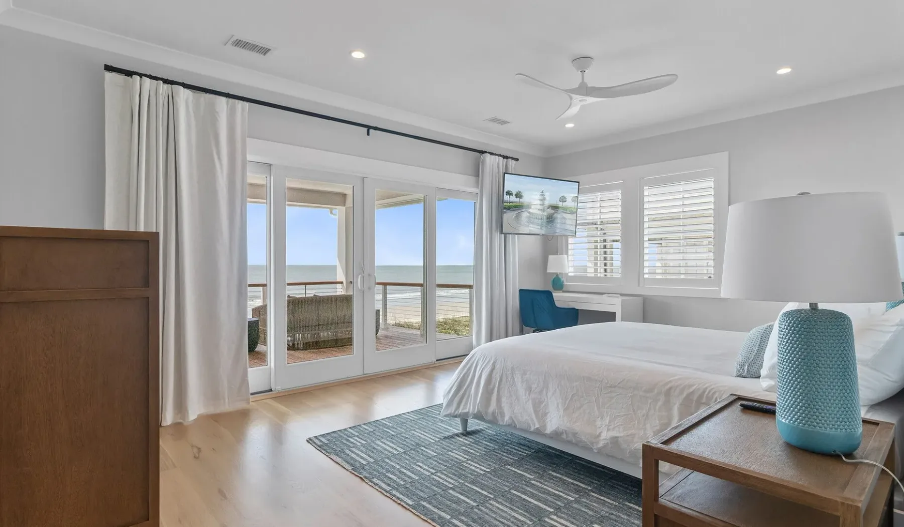 Un dormitorio luminoso con una cama, puertas de vidrio y vistas al agua.