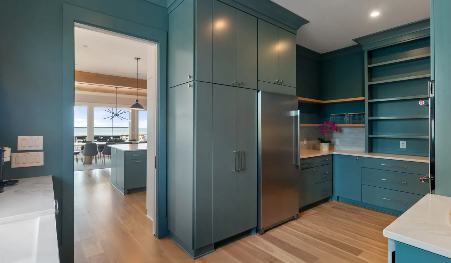 Una cocina verde azulado con refrigerador, encimera y estantes abiertos.
