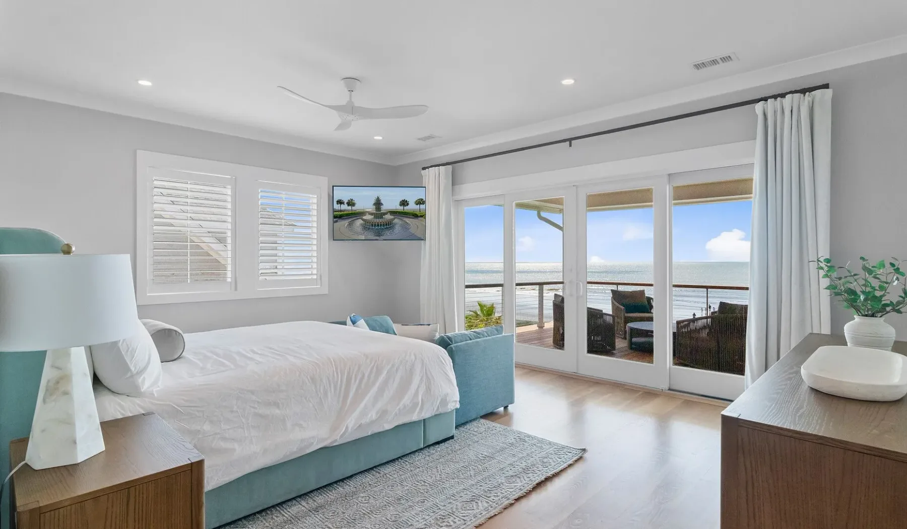 Un dormitorio luminoso da a un balcón con vistas al mar.