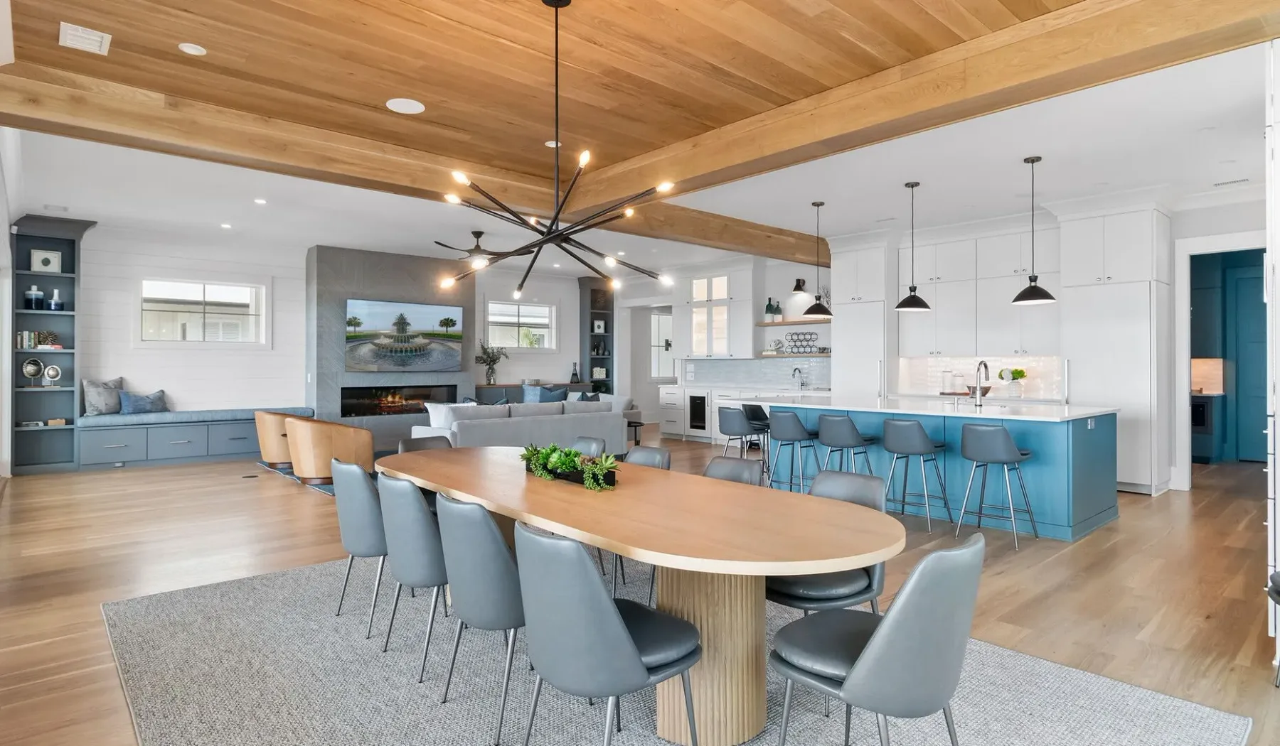 Una cocina y comedor de concepto abierto con una mesa larga de madera y gabinetes azules.