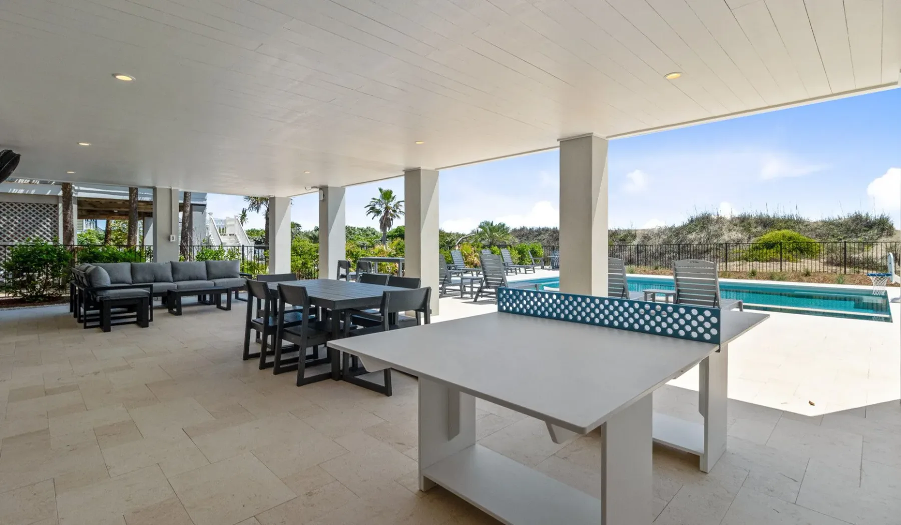 Comedor exterior cubierto con mesas junto a una piscina.