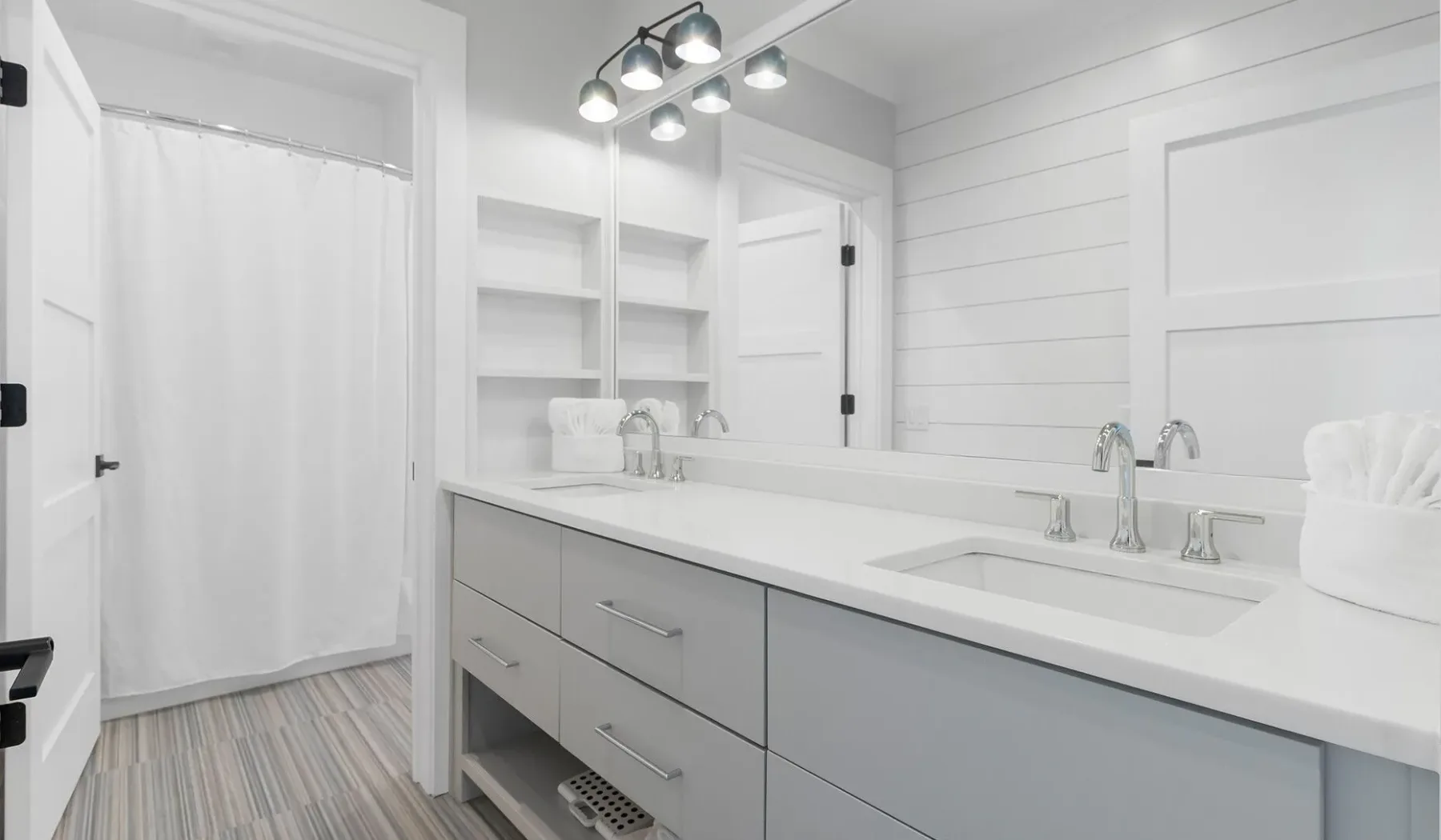 Un baño luminoso con un tocador largo, lavabo y un gran espejo de pared.