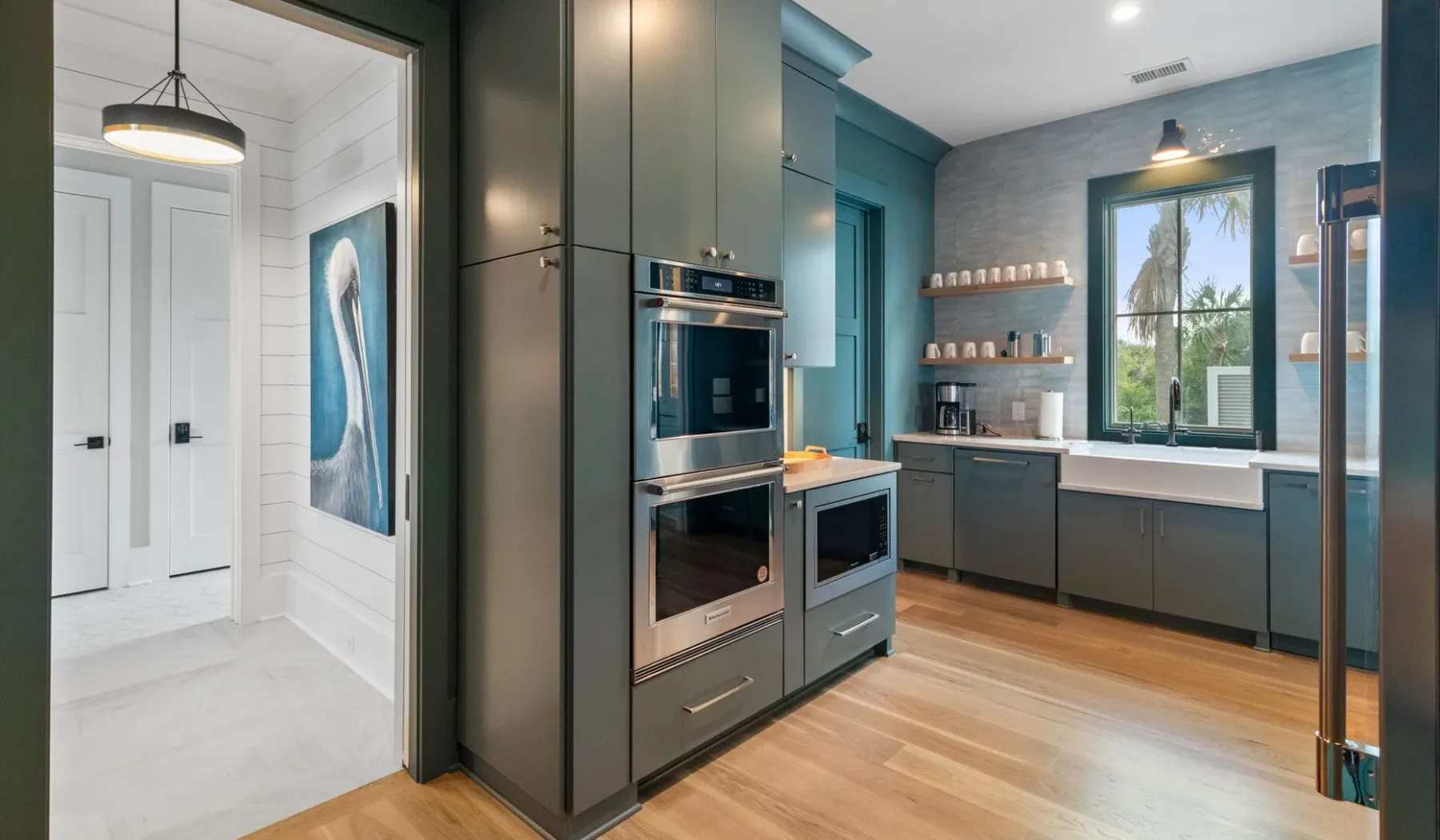 Una cocina moderna con gabinetes oscuros, electrodomésticos de acero inoxidable y una ventana.