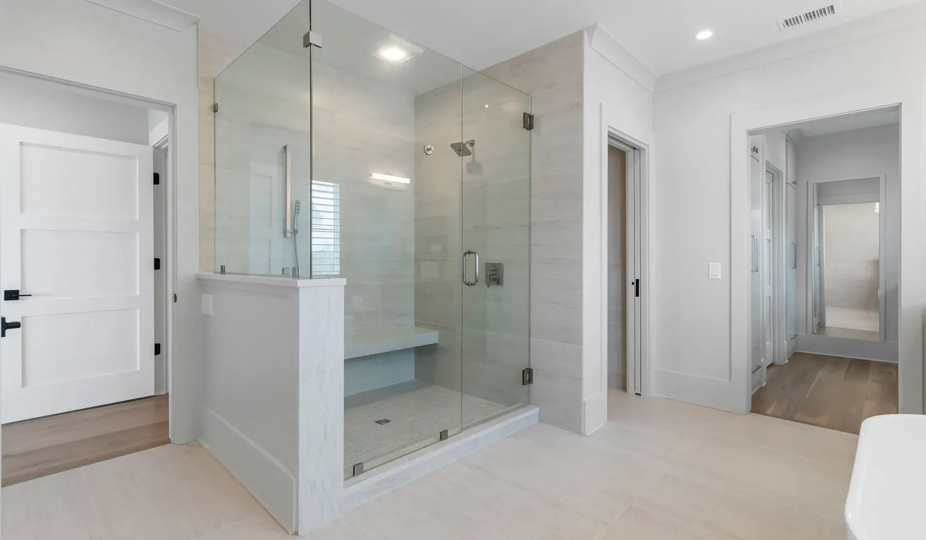 Un baño luminoso cuenta con una ducha de vidrio y paredes de tonos claros.