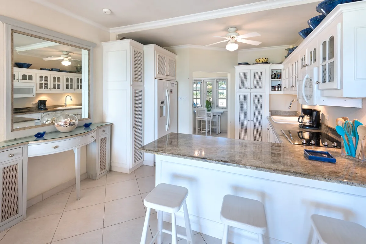A bright kitchen with white cabinetry, a large island, and bar stools.