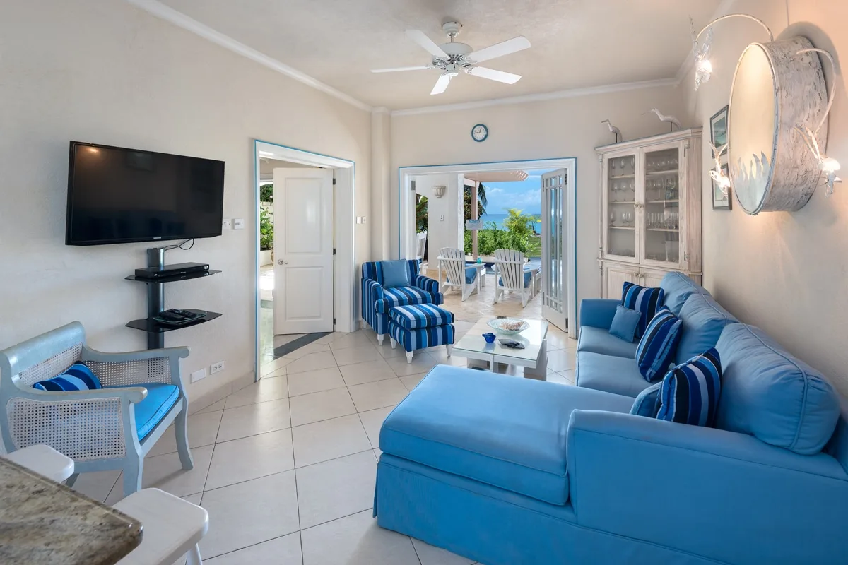 A bright living room with blue seating and open doors leading to a patio.