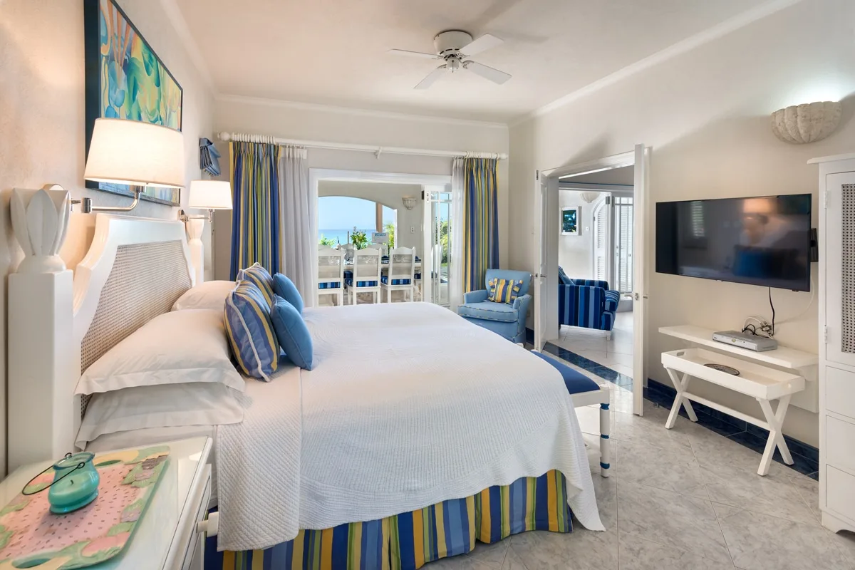 A bright bedroom with a large bed and a seating area by the windows.