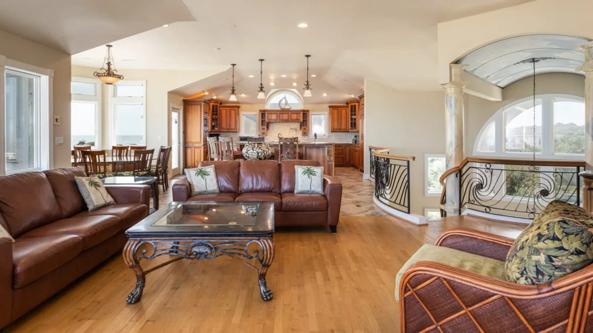 A living room with leather seating and an open kitchen in the background.