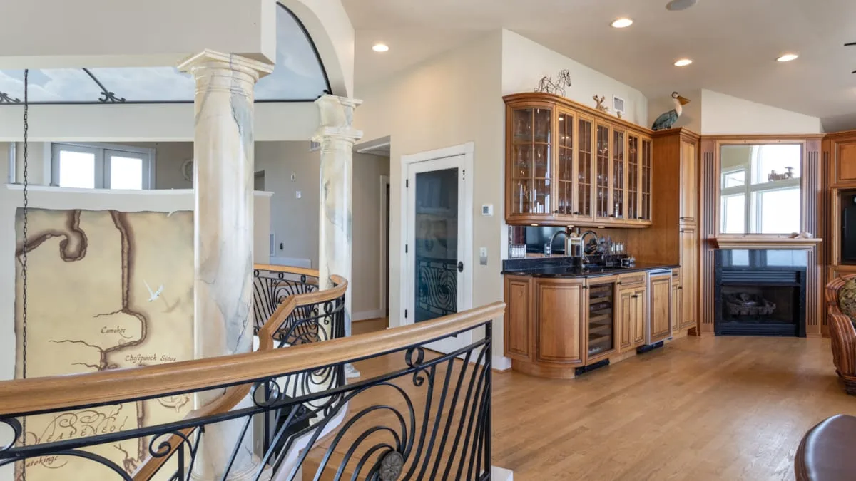 An open interior with a kitchen, wood cabinetry, and a curved railing.