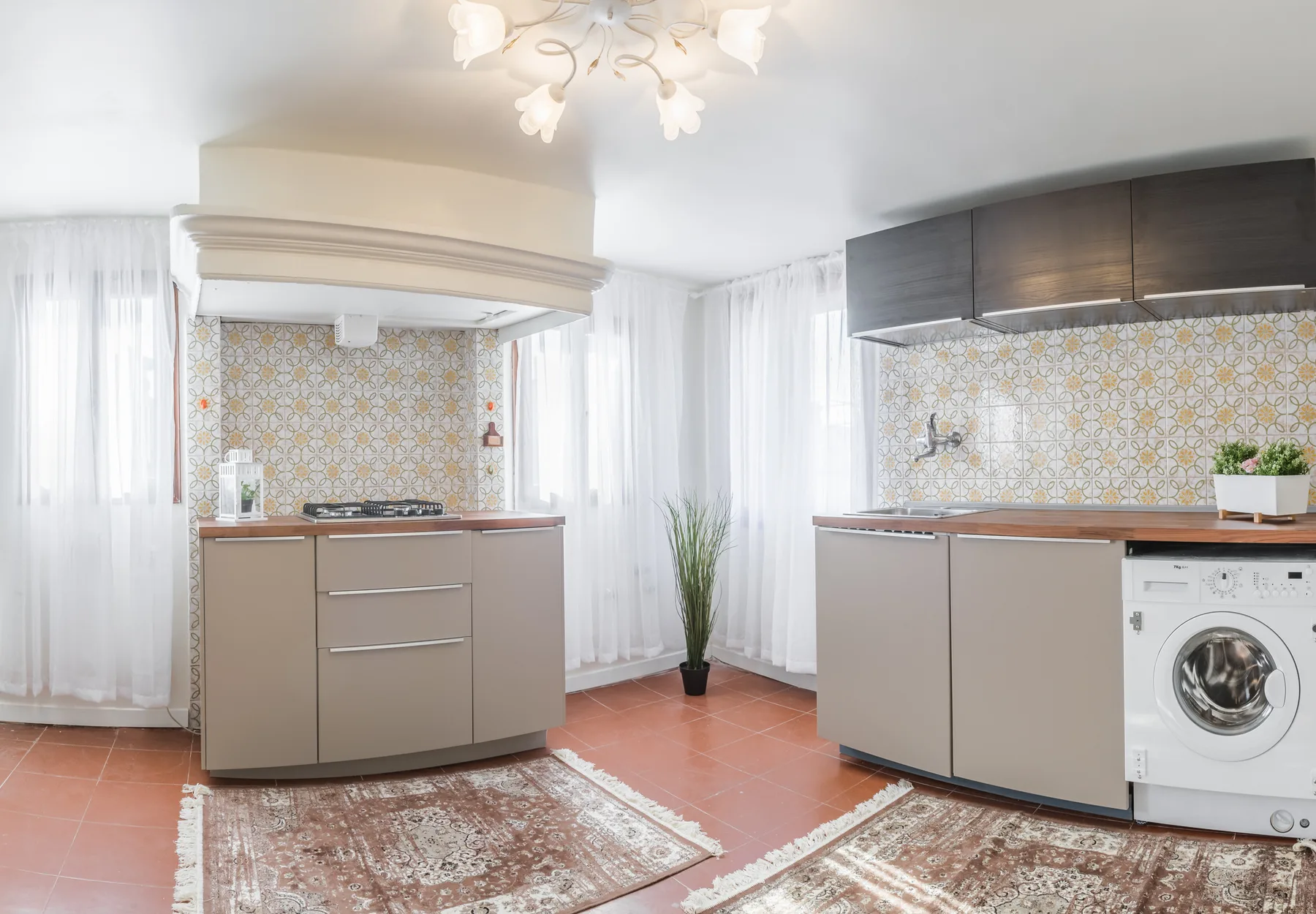 Una cocina luminosa con azulejos, armarios y una lavadora.
