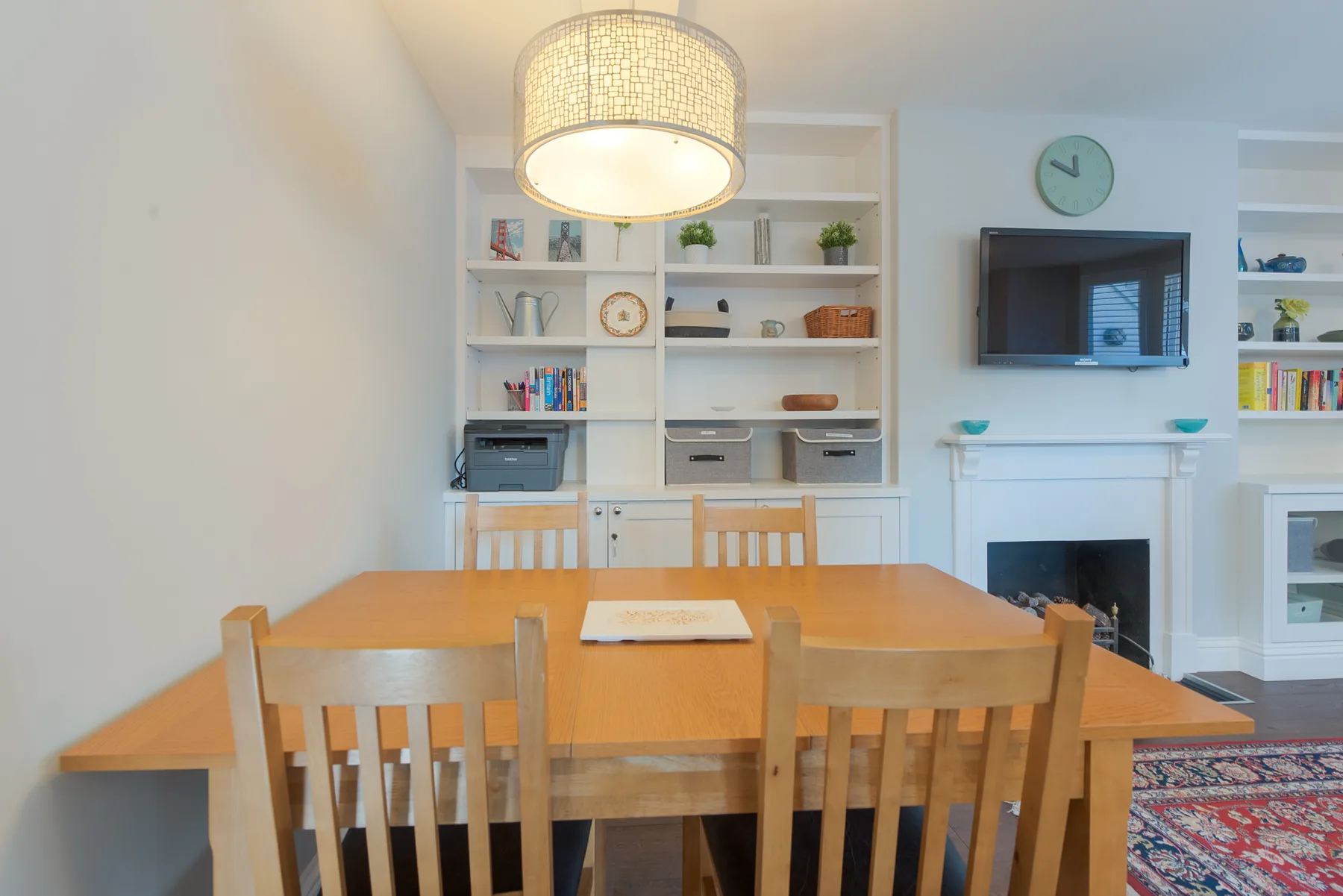 A dining area with a wooden table, chairs, and built-in shelving.