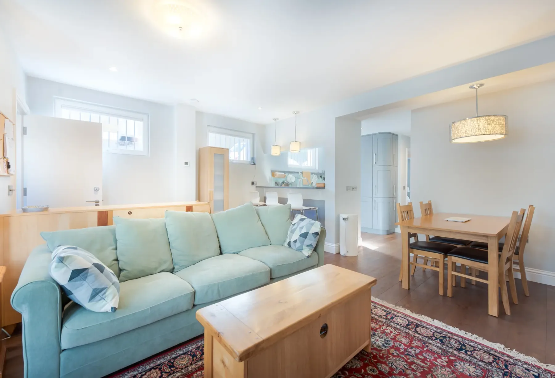 A bright living and dining area with seating, a wooden coffee table, and a dining table.