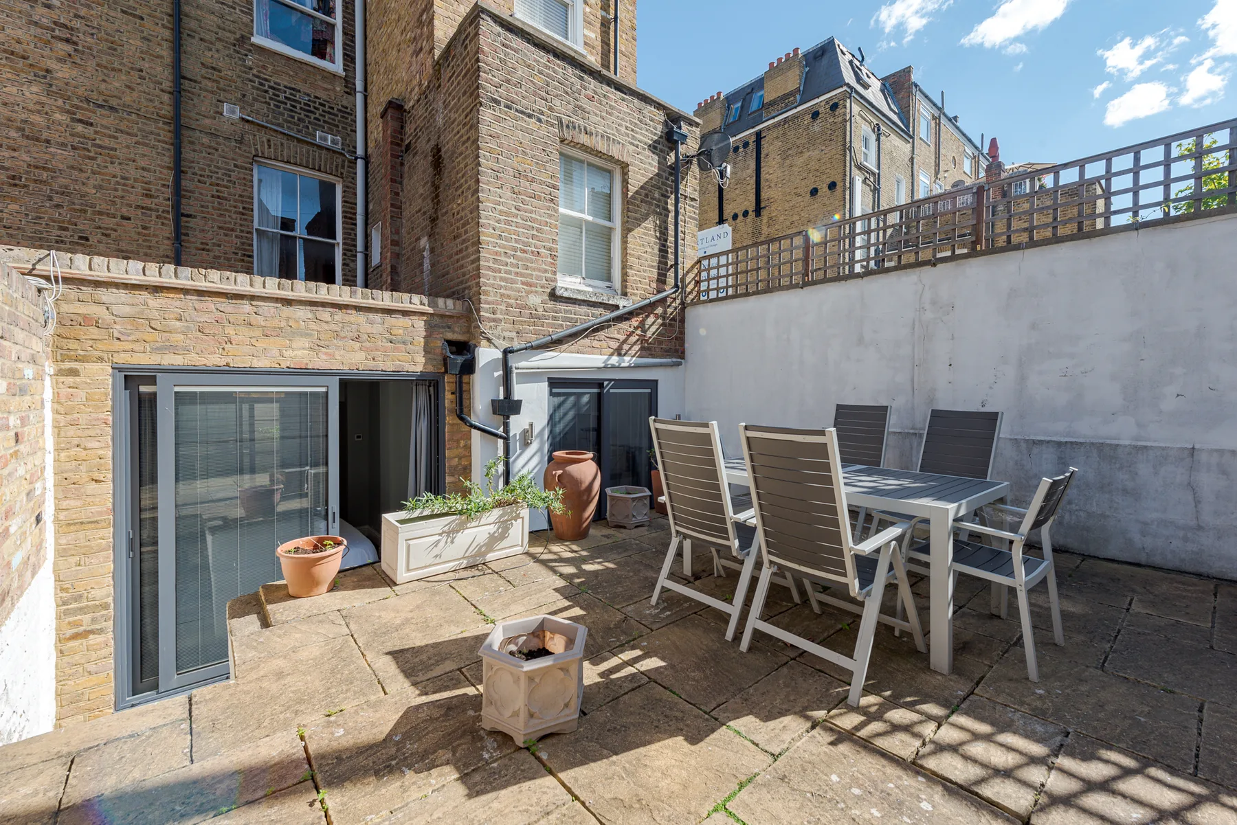A paved courtyard patio with an outdoor dining table and seating.