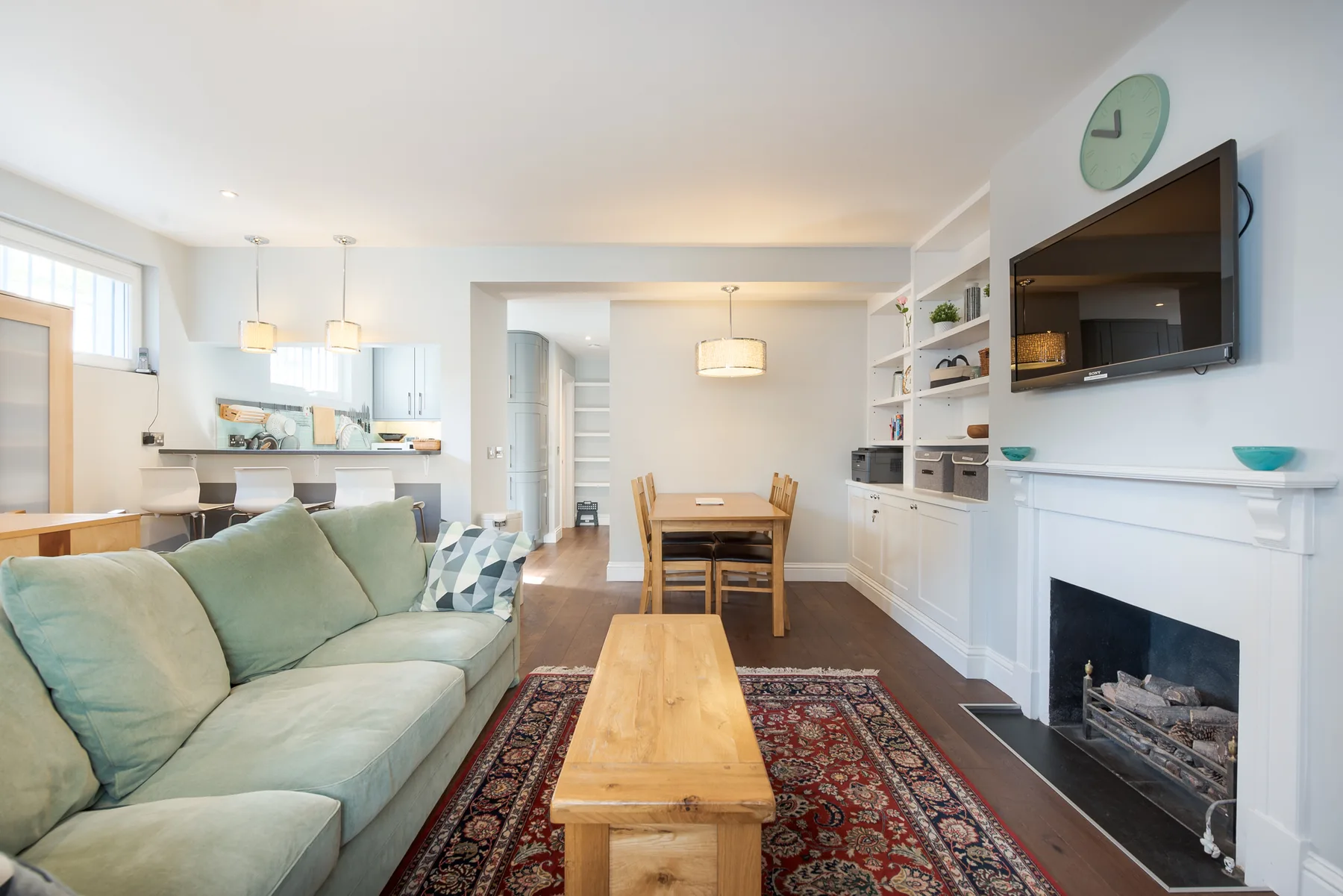 Open-plan living and dining area with a sofa, wooden table, and fireplace.
