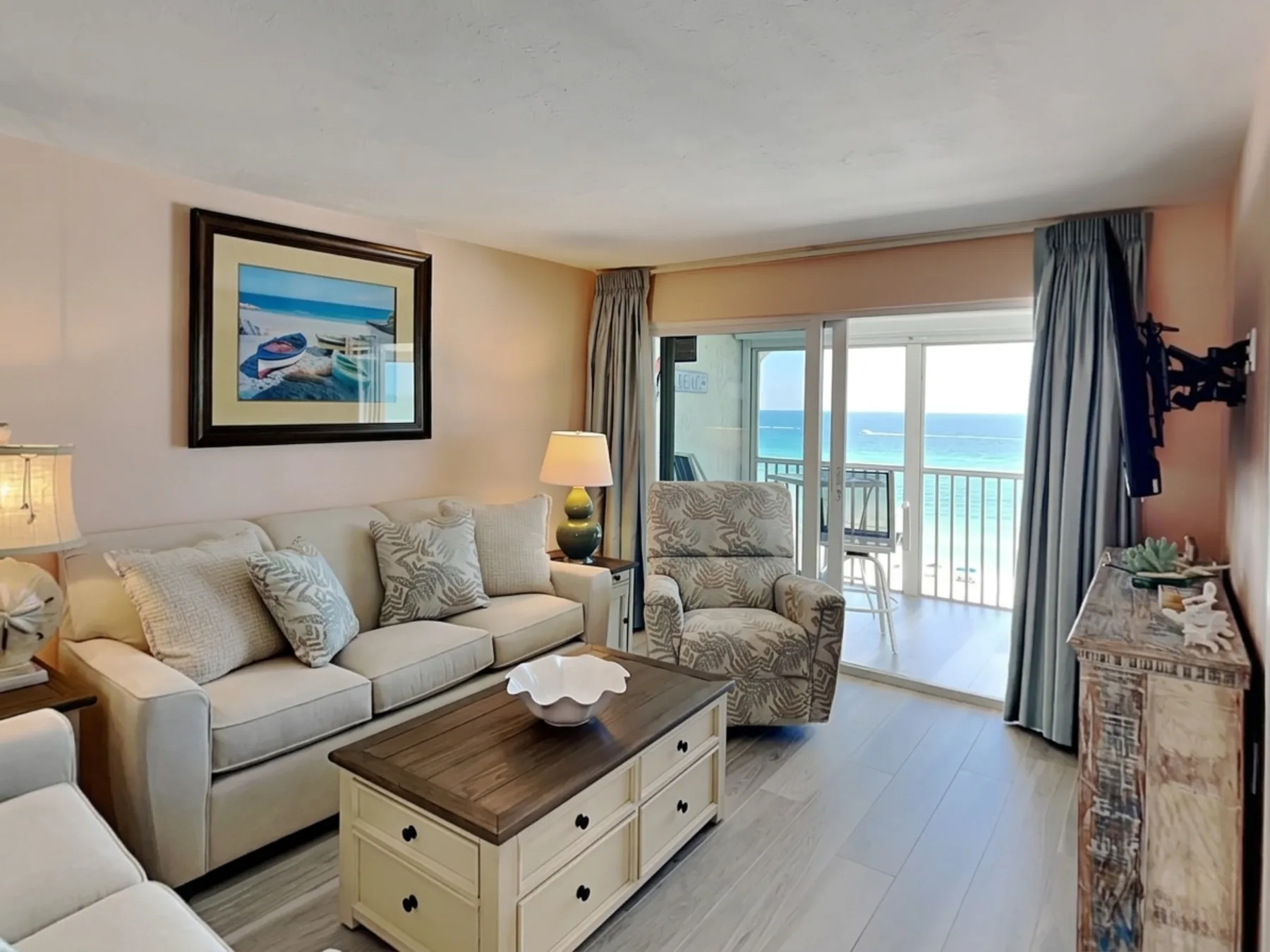 A living room with seating and a coffee table facing sliding glass doors to a balcony.