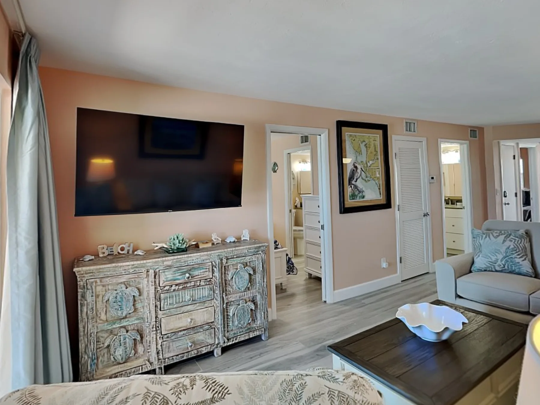 A living room with a wall-mounted television, a cabinet, and seating.
