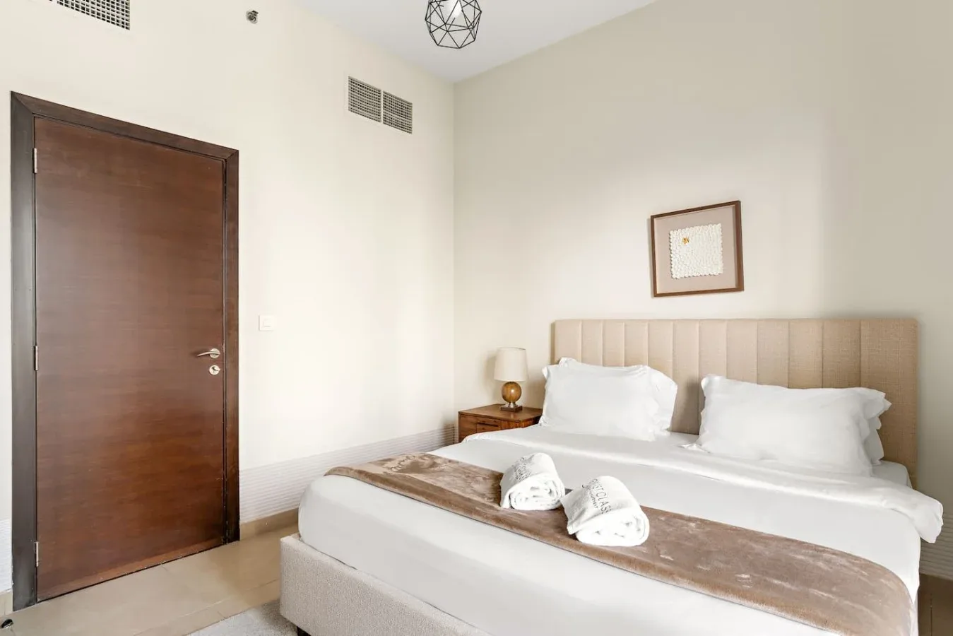 A bedroom with a large bed, white bedding, and a padded headboard.