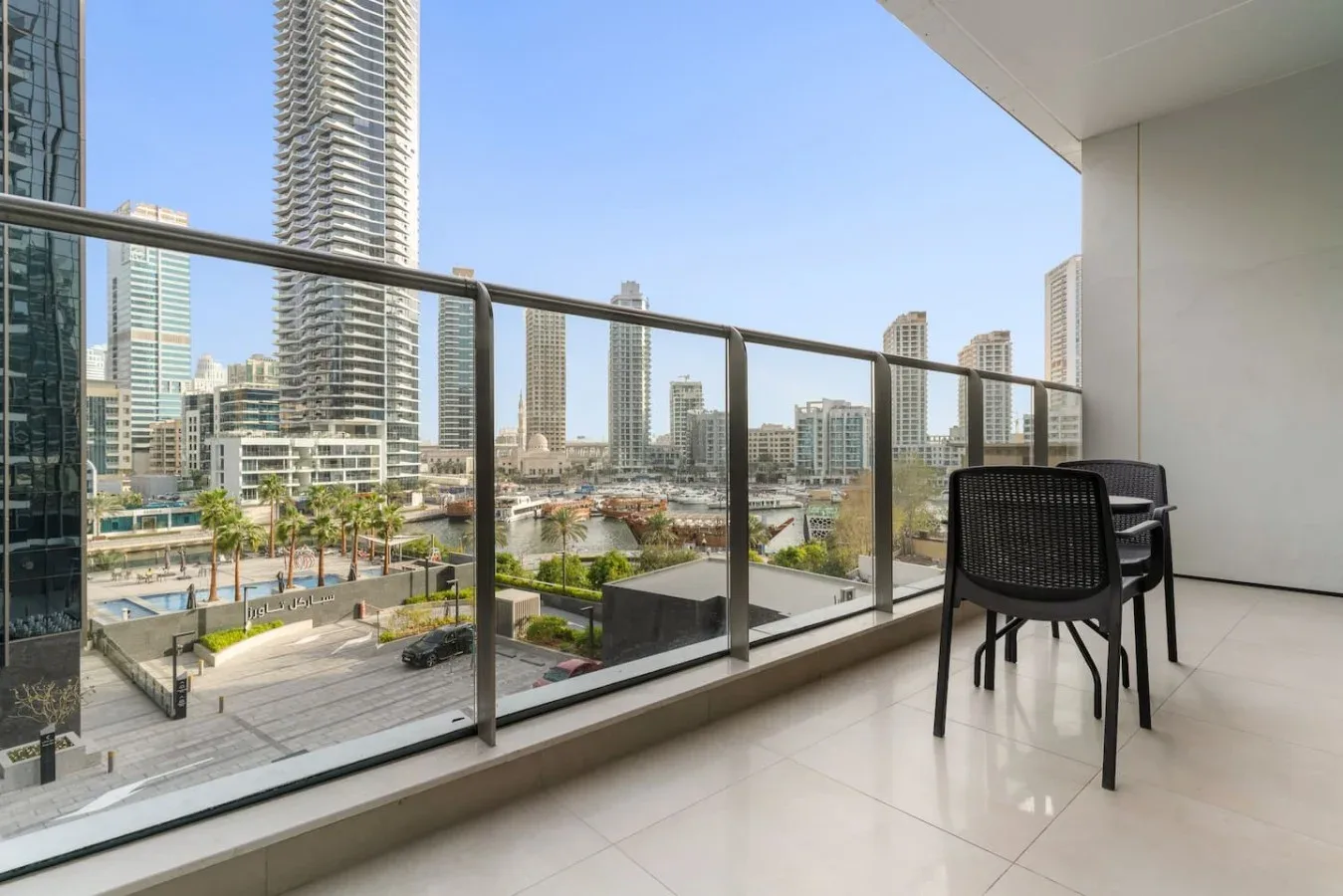 A balcony overlooks a marina, with seating beside the glass railing.